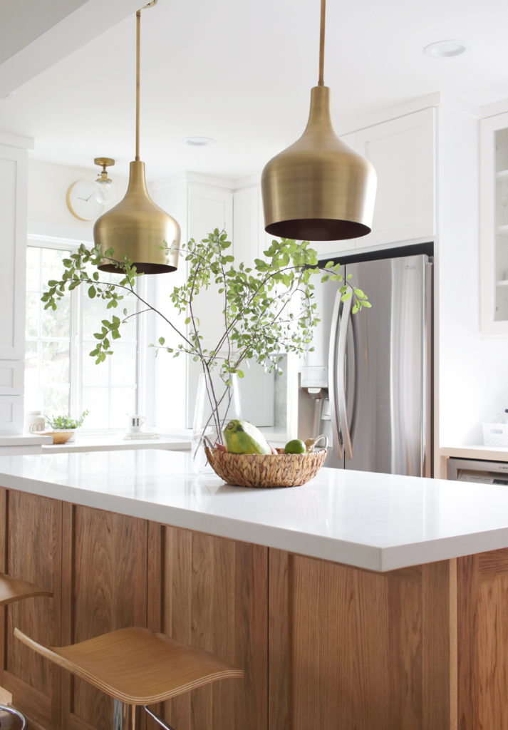 White kitchen with oak island and brass pendatns