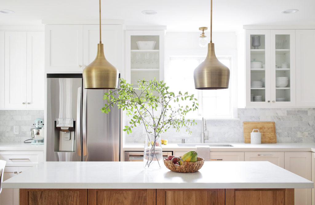 white kitchen with oak island and brass pendants
